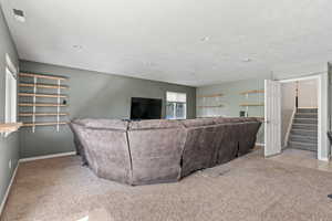 Carpeted living area featuring baseboards, visible vents, stairway, and a textured ceiling