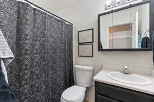 Bathroom with a shower with curtain, toilet, and vanity