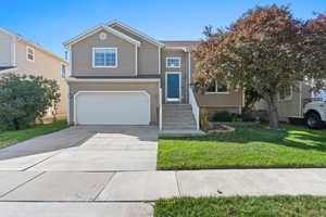 View of front of house with concrete driveway, a garage, and a front lawn