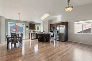 Kitchen featuring decorative backsplash, light countertops, light wood finished floors, stainless steel appliances, and a center island