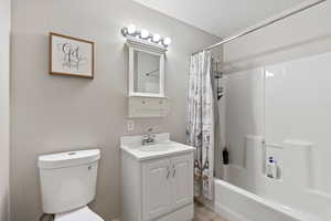 Full bath with toilet, vanity, shower / bathtub combination with curtain, and tile patterned flooring