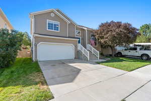 View of front facade with driveway, an attached garage, fence, and a front lawn