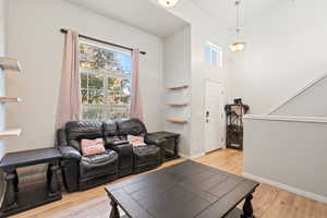Living area with a towering ceiling, baseboards, and light wood finished floors