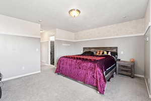 Carpeted bedroom featuring baseboards, a textured ceiling, visible vents, and wallpapered walls