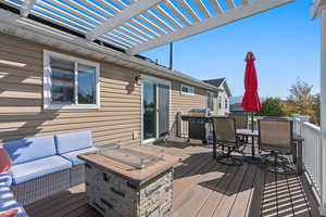 Wooden terrace with an outdoor hangout area, outdoor dining space, grilling area, and a pergola