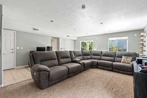 Living area with a textured ceiling, visible vents, baseboards, and light tile patterned floors