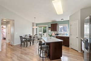 Kitchen with light countertops, a kitchen bar, a kitchen island, light wood-style floors, and backsplash