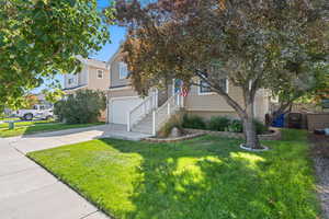 View of property hidden behind natural elements with an attached garage, concrete driveway, and a front yard