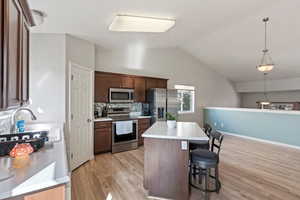 Kitchen with light countertops, a kitchen breakfast bar, appliances with stainless steel finishes, a center island, and light wood-type flooring