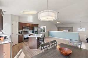 Dining space with baseboards, lofted ceiling, and light wood-style floors