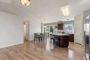 Kitchen featuring light countertops, a center island, lofted ceiling, and light wood finished floors