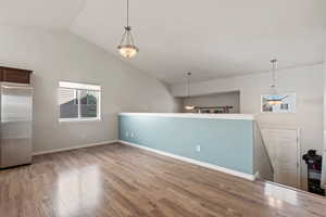 Spare room featuring baseboards, lofted ceiling, and light wood finished floors