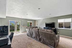 Living room with baseboards, carpet flooring, and a textured ceiling