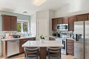 Kitchen with light countertops, tasteful backsplash, light wood-type flooring, stainless steel appliances, and a sink