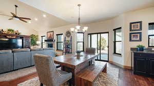 Dining room featuring baseboards, dark wood-style flooring, lofted ceiling, and a fireplace