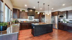 Kitchen featuring dark stone counters, a sink, hardwood / wood-style floors, and appliances with stainless steel finishes