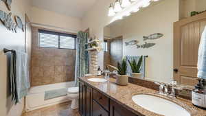 Full bathroom with shower / bath combo, double vanity, a sink, and toilet