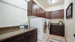 Laundry area featuring a textured ceiling, washer and dryer, cabinet space, and light tile patterned floors