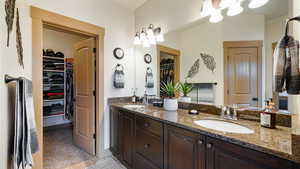 Bathroom featuring double vanity, a spacious closet, a sink, and tile patterned floors