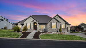 French country style house featuring a lawn, driveway, stucco siding, and stone siding