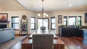 Dining area with baseboards, dark wood-style flooring, a fireplace, and a notable chandelier