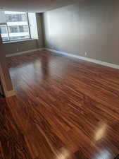 Living room featuring dark wood-style flooring and baseboards.  The condo is fully furnished.