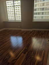 Spare room with baseboards and dark wood finished floors.  The condo is currently fully furnished.