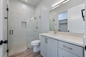 Full bathroom with a shower stall, toilet, wood finished floors, and vanity