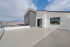 Back of property featuring a tile roof, a balcony, a mountain view, and stucco siding