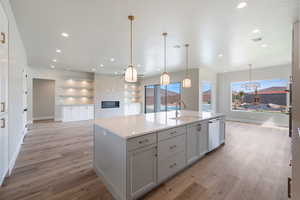 Kitchen with a sink, light wood finished floors, open floor plan, dishwashing machine, and visible vents