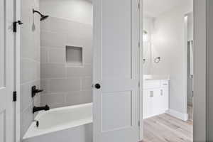Full bathroom with baseboards, wood finished floors, shower / bathing tub combination, and vanity