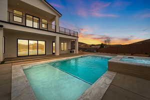 Pool at dusk featuring a patio, fence, a fenced in pool, and an in ground hot tub