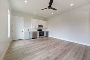 Kitchen with baseboards, visible vents, white cabinets, a ceiling fan, and appliances with stainless steel finishes