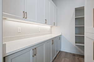Laundry room with dark wood-type flooring and baseboards
