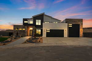 Contemporary house with stone siding, stucco siding, concrete driveway, and a garage