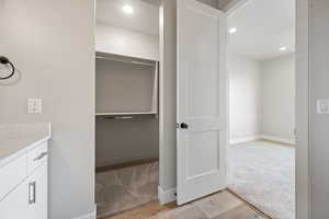 Bathroom featuring baseboards, recessed lighting, wood finished floors, and vanity