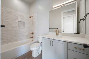 Full bath with toilet, vanity, shower combination, and wood finished floors