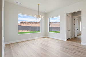Spare room featuring visible vents, a chandelier, and wood finished floors