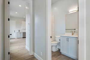 Full bath with toilet, wood finished floors, decorative backsplash, and vanity