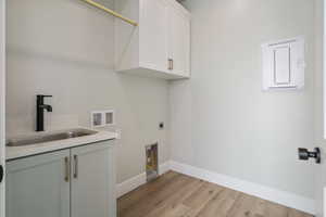 Washroom with hookup for a washing machine, baseboards, a sink, hookup for an electric dryer, and cabinet space