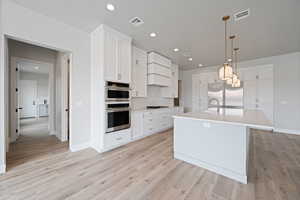 Kitchen featuring light countertops, a kitchen island with sink, appliances with stainless steel finishes, and visible vents