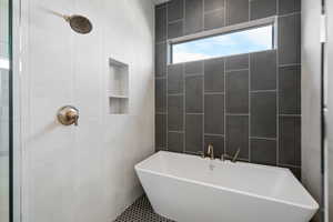 Bathroom with tile walls, a tile shower, and a soaking tub