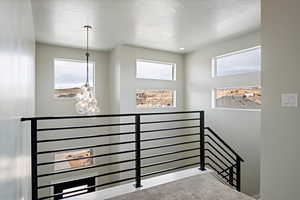 Stairway featuring a textured ceiling and a chandelier