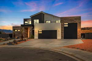 Contemporary home with driveway, stone siding, stucco siding, an attached garage, and a balcony