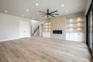 Unfurnished living room featuring stairs, recessed lighting, baseboards, light wood-style floors, and visible vents