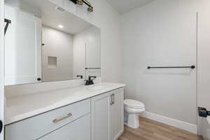 Bathroom featuring visible vents, baseboards, toilet, wood finished floors, and vanity