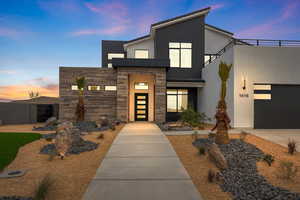Modern home with concrete driveway, stucco siding, fence, stone siding, and a garage