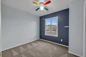 Carpeted empty room featuring a ceiling fan, baseboards, and visible vents
