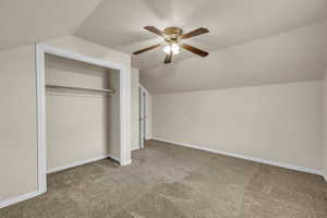 Unfurnished bedroom featuring vaulted ceiling, a closet, and carpet floors
