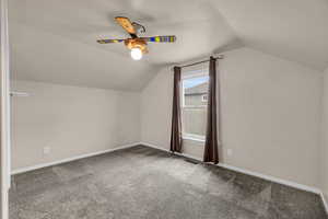 Additional living space featuring carpet flooring, visible vents, baseboards, ceiling fan, and lofted ceiling